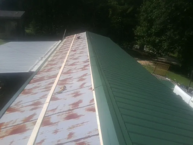 Old rusted panels beside newly installed green metal roofing — Wind Damage Roof Repair by Roofing Brothers in Marlow