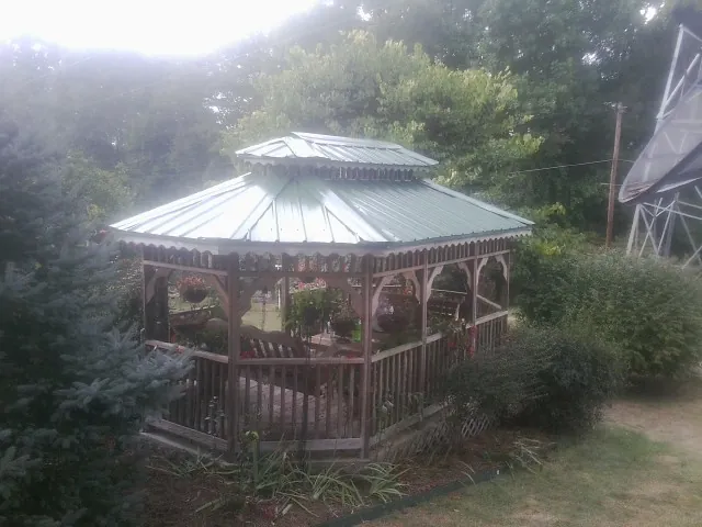 Green metal roof on a backyard gazebo surrounded by garden beds in Marlow