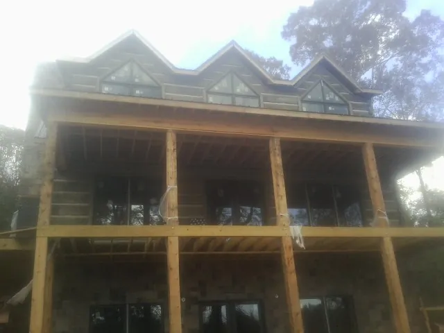 Dormers and porch framing on a large log home under construction — Roof Coating work by our crew in Marlow