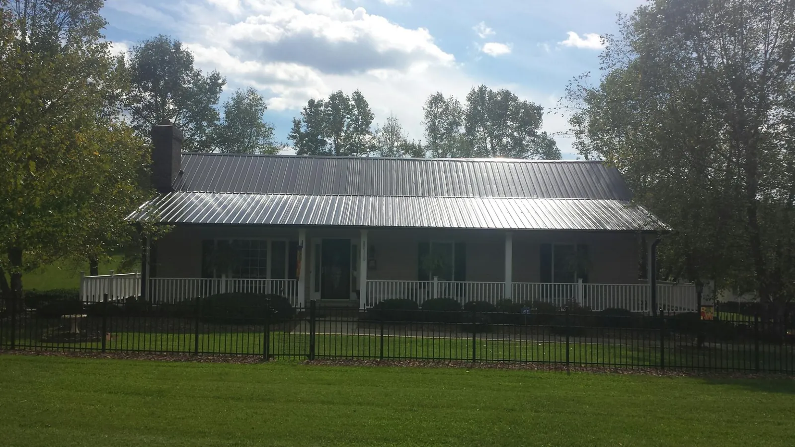 Gray metal roof on a brick ranch with a full width front porch — Gutter Guard Installation work by our crew in Marlow