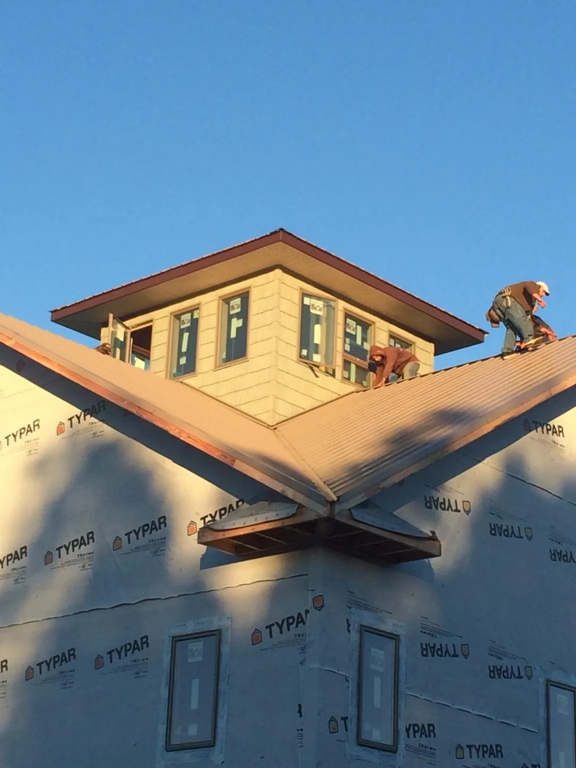 Roofers working around a rooftop cupola on a new metal roof at sunset — Roof Waterproofing in Marlow by Roofing Brothers